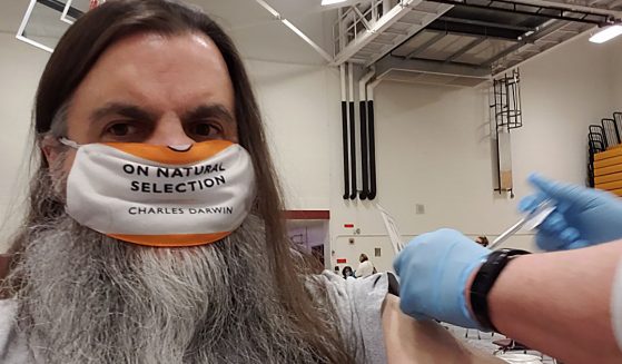 Man receives COVID jab wearing mask that says "On Natural Selection - Charles Darwin"