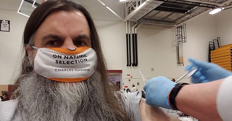 Man receives COVID jab wearing mask that says "On Natural Selection - Charles Darwin"